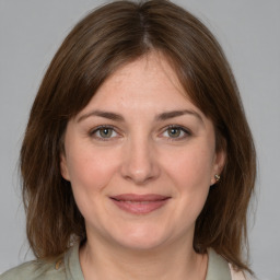 Joyful white young-adult female with medium  brown hair and grey eyes