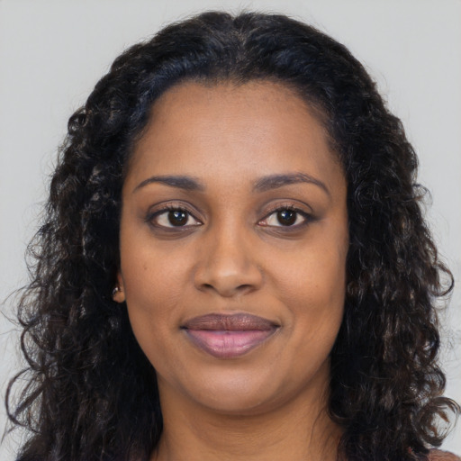 Joyful black young-adult female with long  black hair and brown eyes