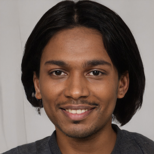 Joyful black young-adult male with medium  black hair and brown eyes