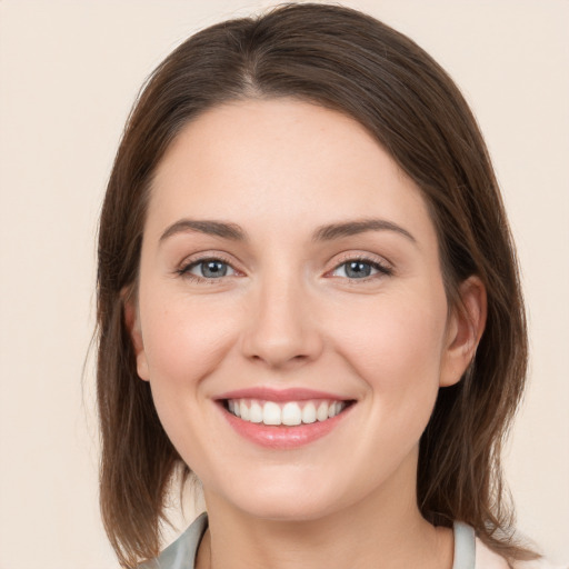 Joyful white young-adult female with medium  brown hair and grey eyes