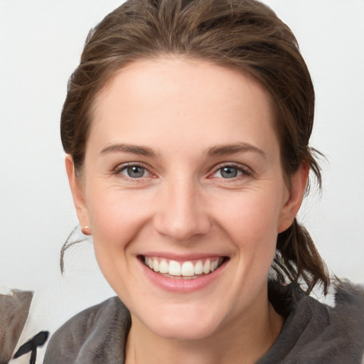 Joyful white young-adult female with medium  brown hair and grey eyes