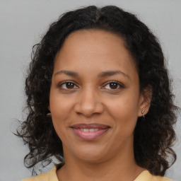 Joyful black adult female with long  brown hair and brown eyes