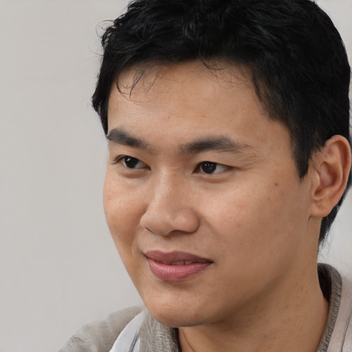 Joyful asian young-adult male with short  black hair and brown eyes