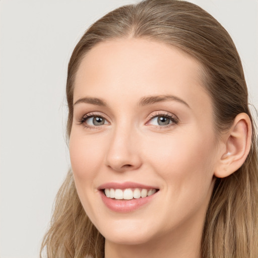 Joyful white young-adult female with long  brown hair and blue eyes