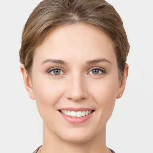 Joyful white young-adult female with short  brown hair and grey eyes