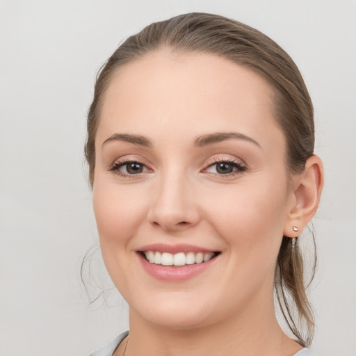 Joyful white young-adult female with medium  brown hair and grey eyes