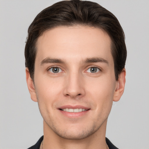 Joyful white young-adult male with short  brown hair and grey eyes