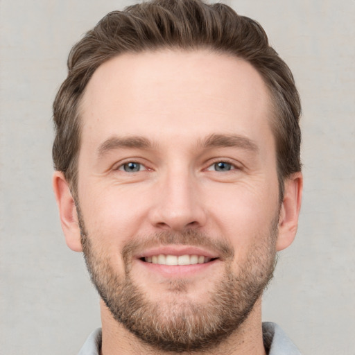 Joyful white young-adult male with short  brown hair and grey eyes