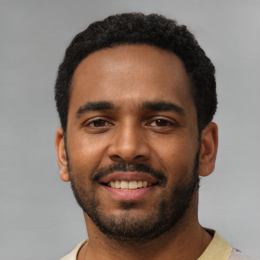 Joyful black young-adult male with short  black hair and brown eyes