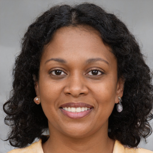 Joyful black young-adult female with long  brown hair and brown eyes
