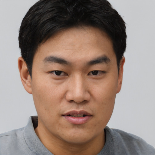 Joyful asian young-adult male with short  black hair and brown eyes