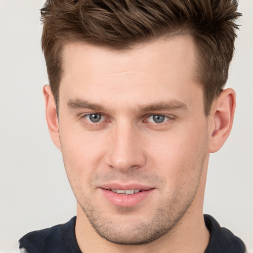 Joyful white young-adult male with short  brown hair and grey eyes