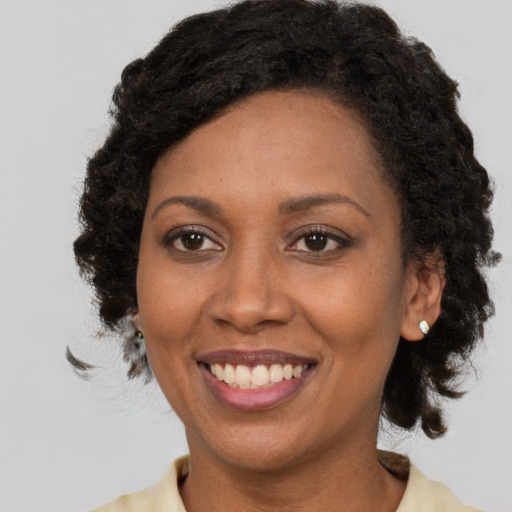 Joyful black adult female with medium  brown hair and brown eyes