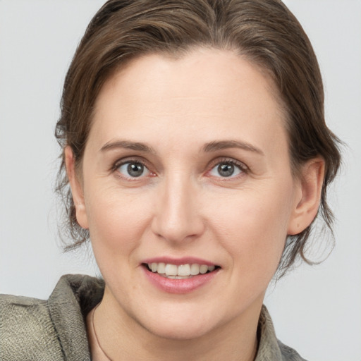 Joyful white young-adult female with medium  brown hair and grey eyes