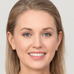 Joyful white young-adult female with long  brown hair and blue eyes