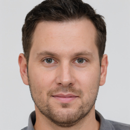 Joyful white young-adult male with short  brown hair and grey eyes