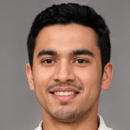 Joyful latino young-adult male with short  black hair and brown eyes