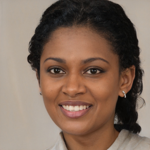 Joyful black young-adult female with long  black hair and brown eyes
