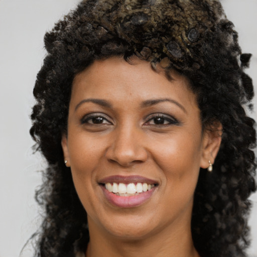 Joyful black young-adult female with long  black hair and brown eyes
