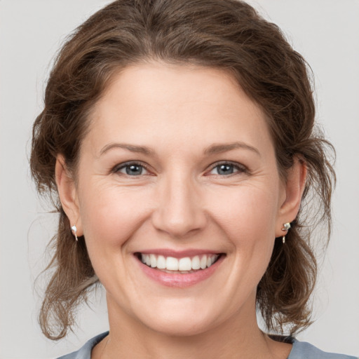 Joyful white young-adult female with medium  brown hair and grey eyes