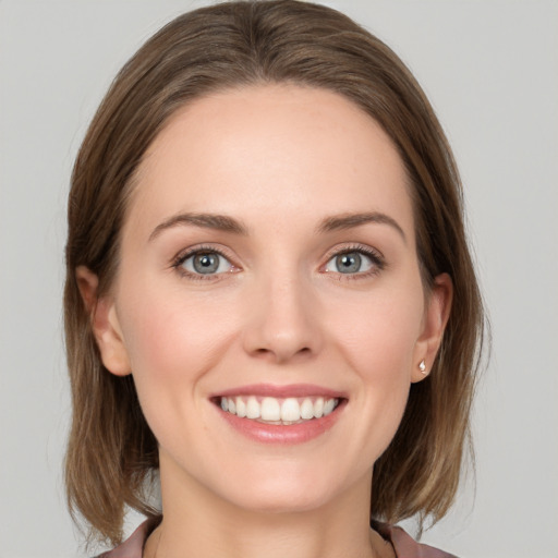 Joyful white young-adult female with medium  brown hair and grey eyes