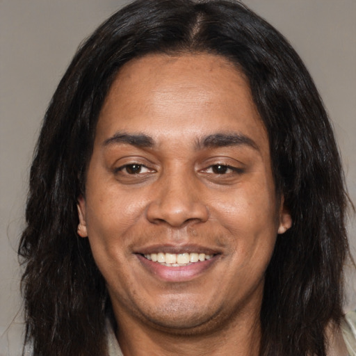 Joyful black adult male with long  brown hair and brown eyes