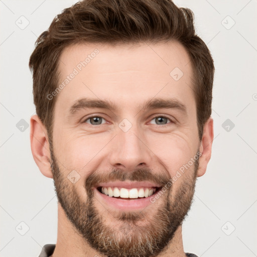 Joyful white young-adult male with short  brown hair and grey eyes