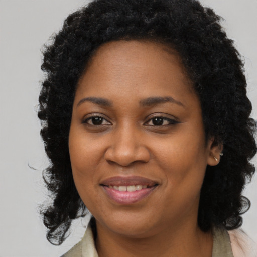 Joyful black young-adult female with long  brown hair and brown eyes