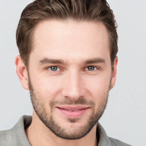 Joyful white young-adult male with short  brown hair and grey eyes