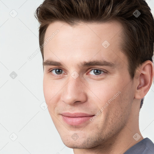 Joyful white young-adult male with short  brown hair and grey eyes