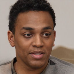 Joyful black young-adult male with short  brown hair and brown eyes