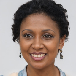 Joyful black young-adult female with long  brown hair and brown eyes