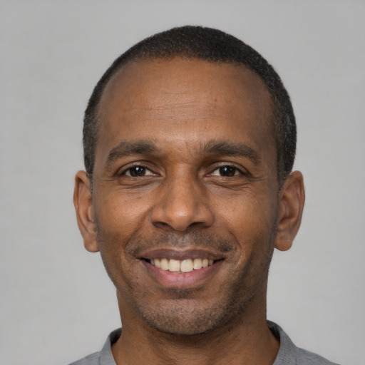 Joyful black adult male with short  black hair and brown eyes