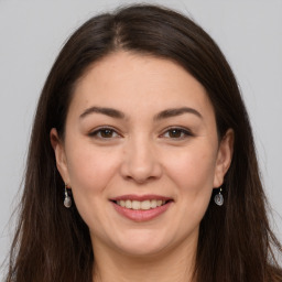 Joyful white young-adult female with long  brown hair and brown eyes