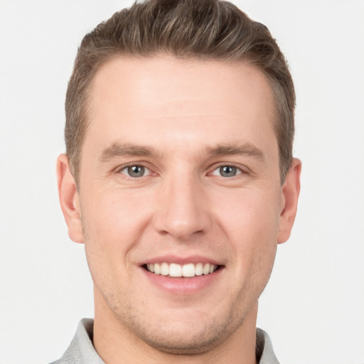 Joyful white young-adult male with short  brown hair and grey eyes