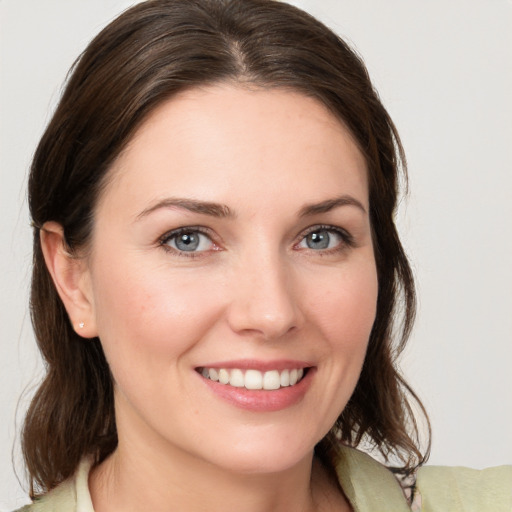 Joyful white young-adult female with medium  brown hair and grey eyes