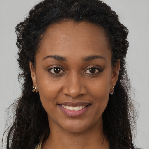 Joyful black young-adult female with long  brown hair and brown eyes
