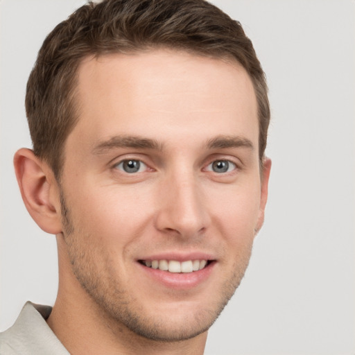 Joyful white young-adult male with short  brown hair and grey eyes