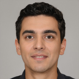 Joyful white young-adult male with short  black hair and brown eyes