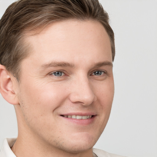 Joyful white young-adult male with short  brown hair and grey eyes