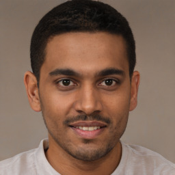 Joyful black young-adult male with short  brown hair and brown eyes