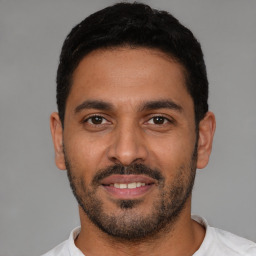 Joyful latino young-adult male with short  black hair and brown eyes