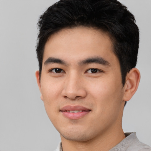 Joyful asian young-adult male with short  brown hair and brown eyes