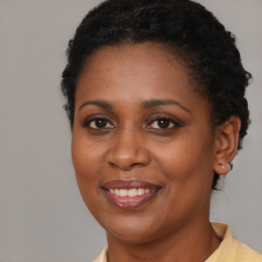 Joyful black young-adult female with short  black hair and brown eyes