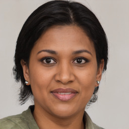 Joyful black adult female with medium  brown hair and brown eyes