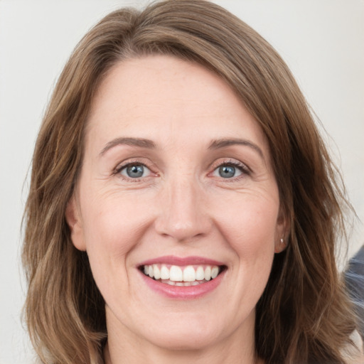 Joyful white adult female with long  brown hair and grey eyes