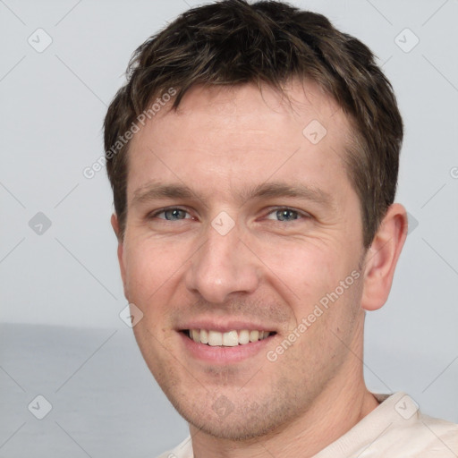 Joyful white young-adult male with short  brown hair and grey eyes