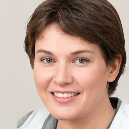 Joyful white young-adult female with medium  brown hair and grey eyes