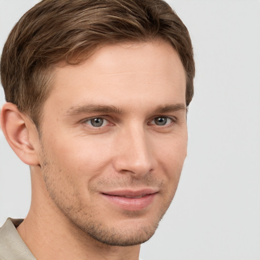 Joyful white young-adult male with short  brown hair and grey eyes