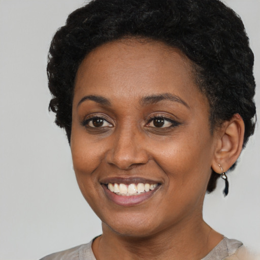 Joyful black young-adult female with short  black hair and brown eyes